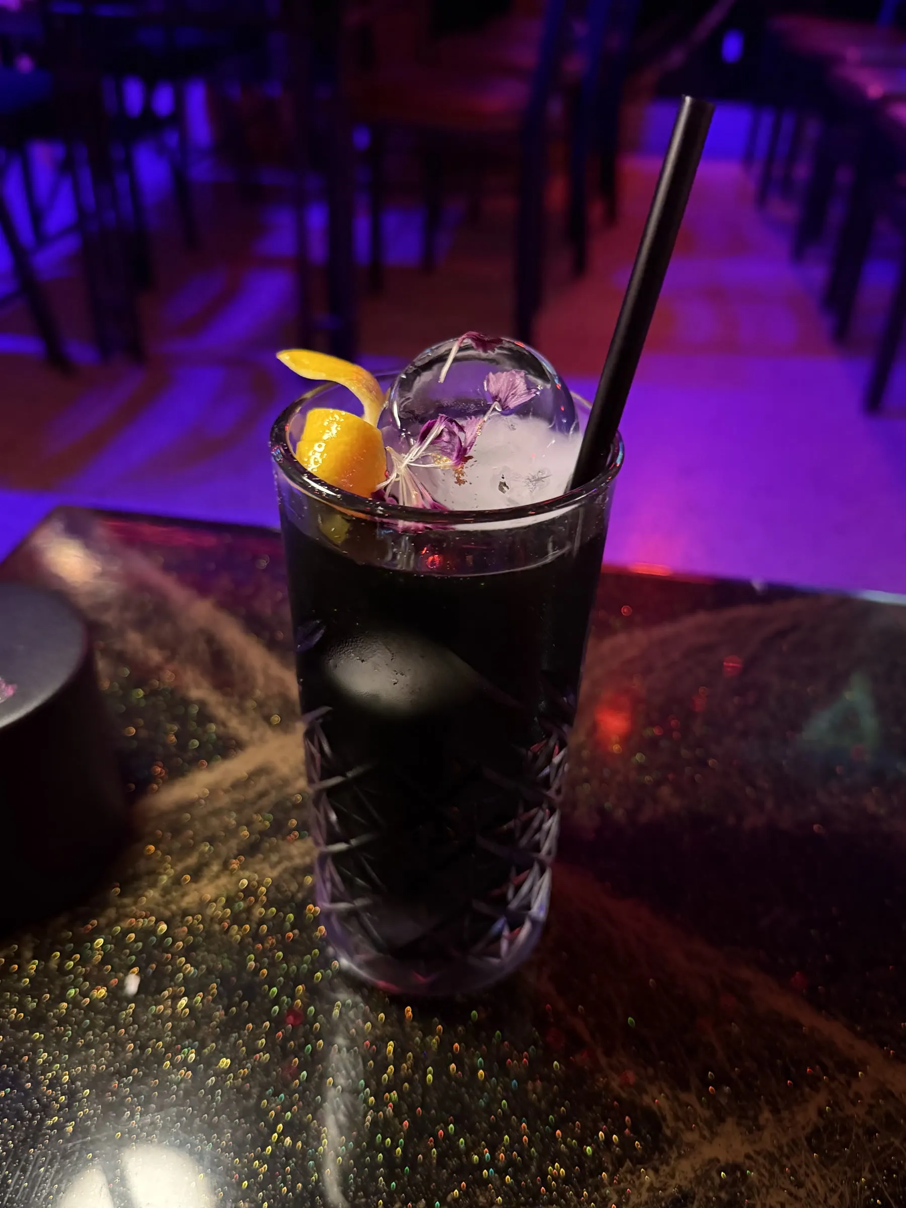 Black Pearl cocktail with orange peel and dried flower