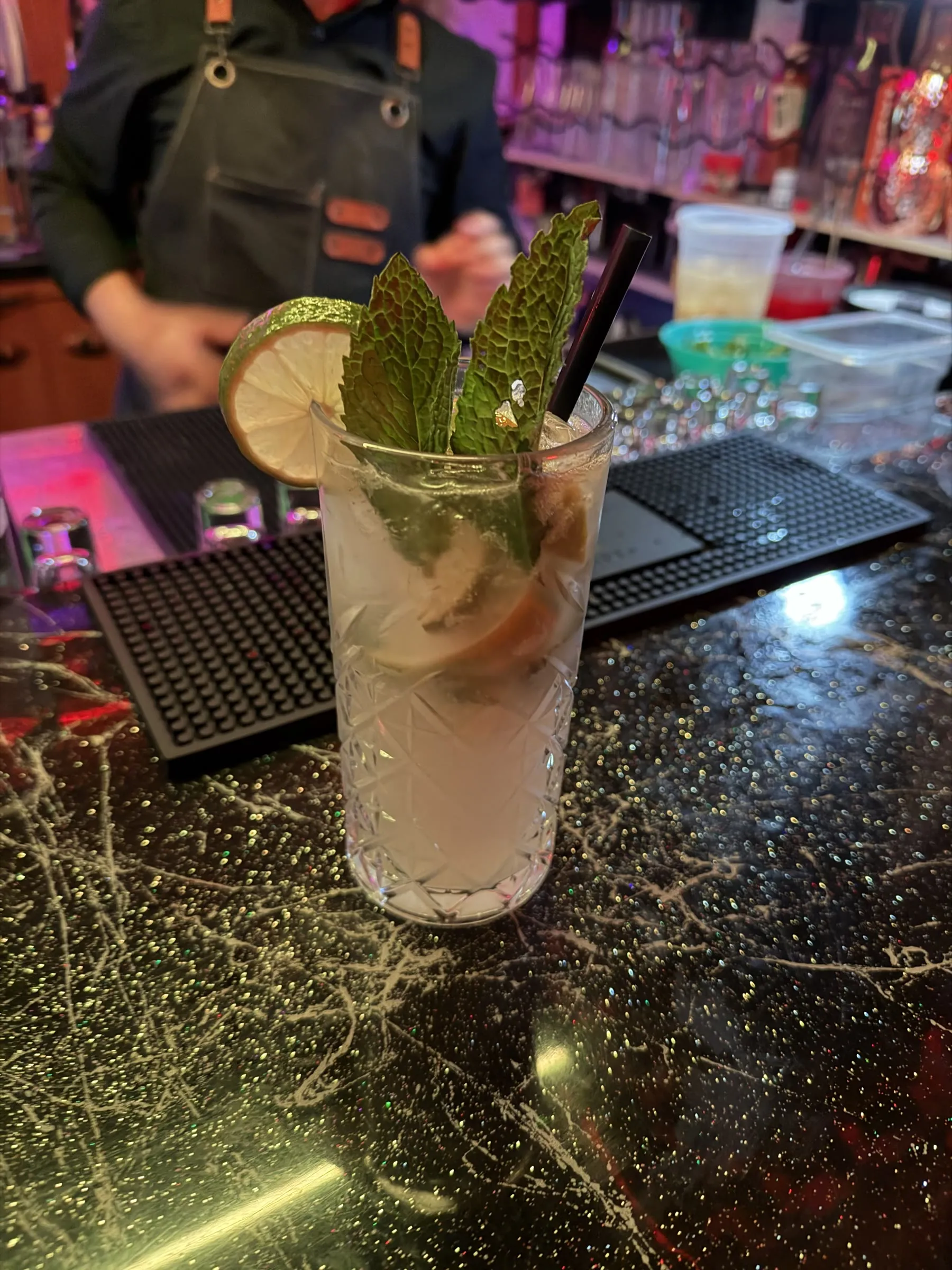Mojito on the bar with the bartender behind it